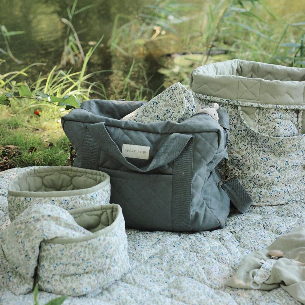 Mum and baby having a picnic on the grass with an Avery Row changing bag in Nutmeg