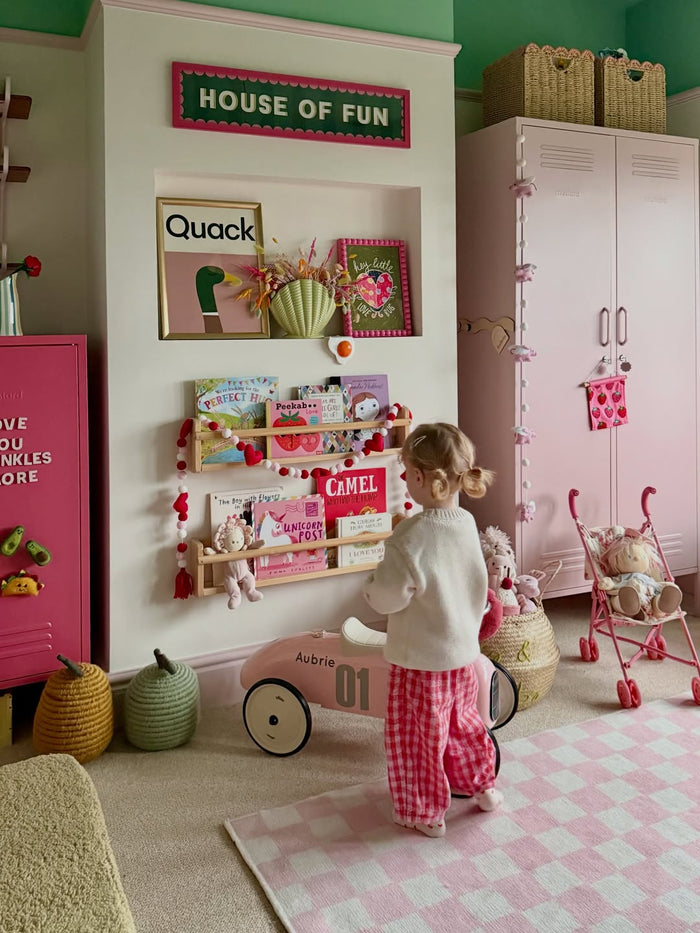 A childs bedrom that features a green stripped wallpaper and teddy basket.
