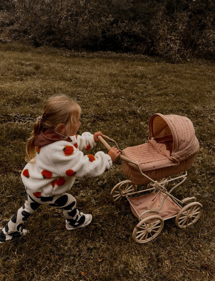 A child walking her dolly in a pink pram