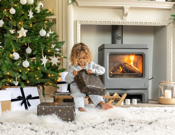 Child opening christmas presents by the fire