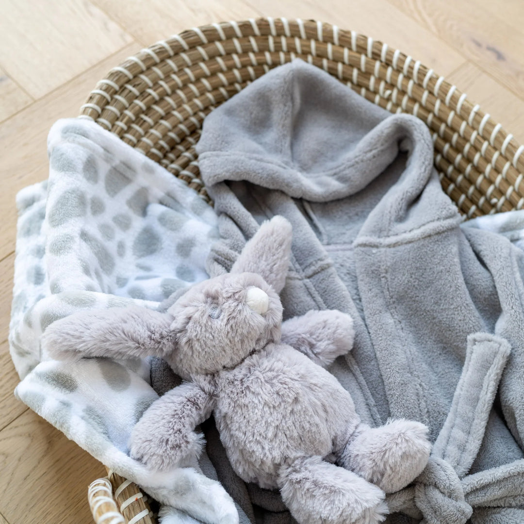 Keel Toys - Beautiful, ultra-soft cuddly toys in a variety of animals. From rattles, to comforters and soft toys to last generations. Image features a little grey keels cuddly toy rabbit on a grey blanket in a changing basket.