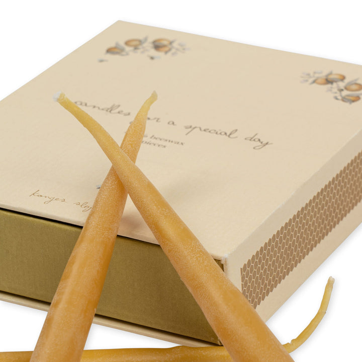 Set of long candles with a decorative box on a white background