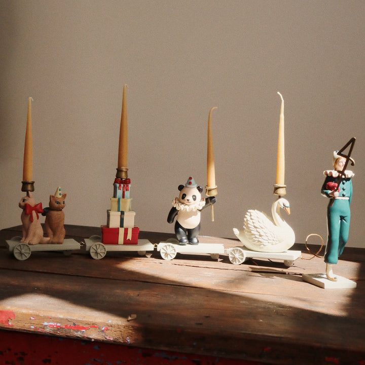 Decorative items including candles, figurines, and a swan on a wooden surface with a neutral background.