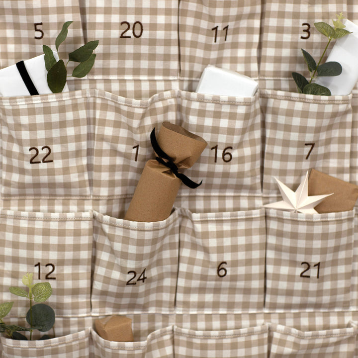 Checkered advent calendar with numbered pockets and small decorative items.