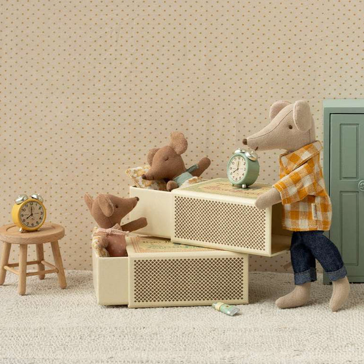 Miniature scene with toy figures in a room setting, including a bed, table, and chairs.